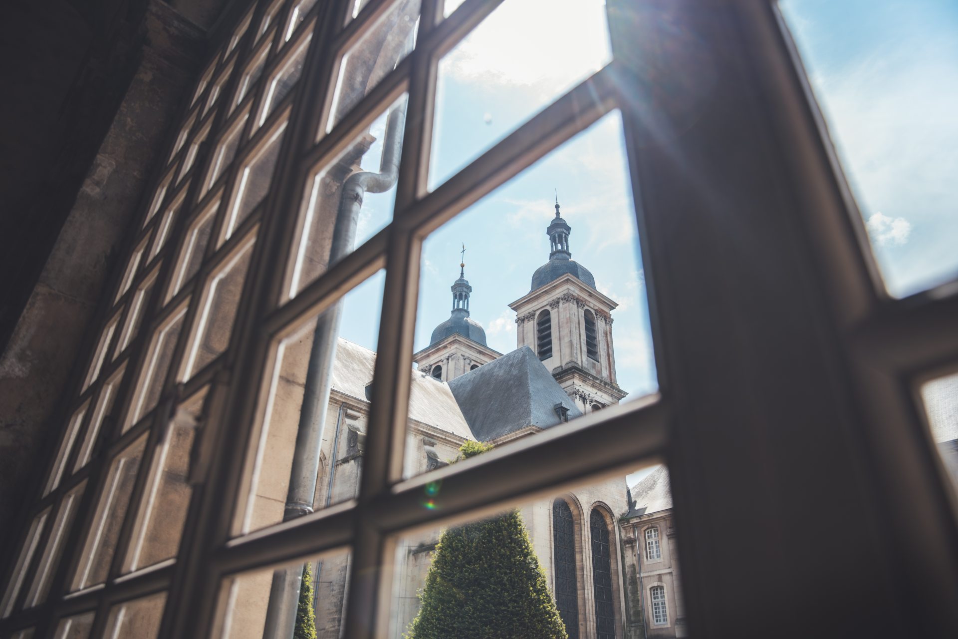 vue de l'abbatiale à travers les fenêtres à meneaux d'un couloir de l'abbaye