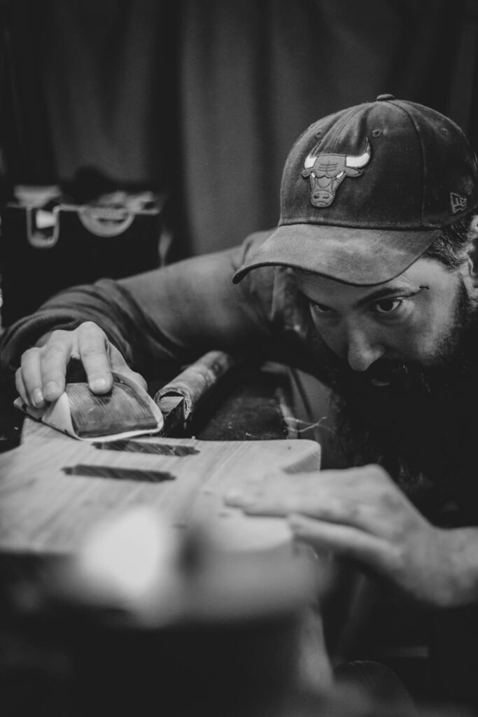 photo en noir et blanc représentant Joey Martin entrain de poncer une guitare