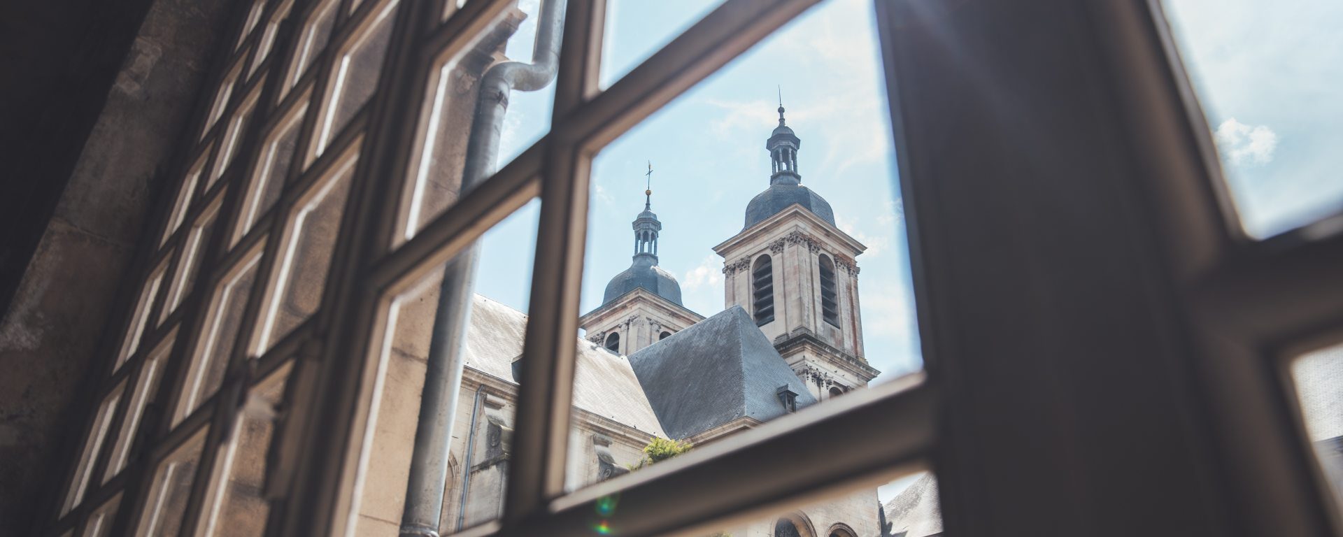 vue de l'abbatiale à travers les fenêtres à meneaux d'un couloir de l'abbaye