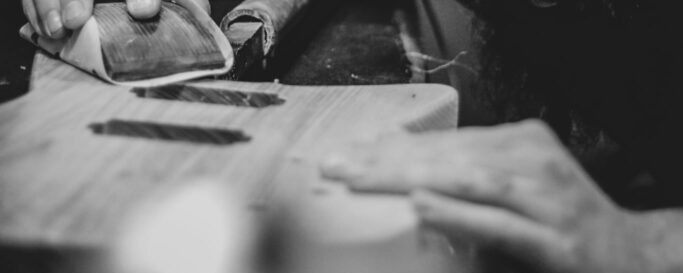 photo en noir et blanc représentant Joey Martin entrain de poncer une guitare